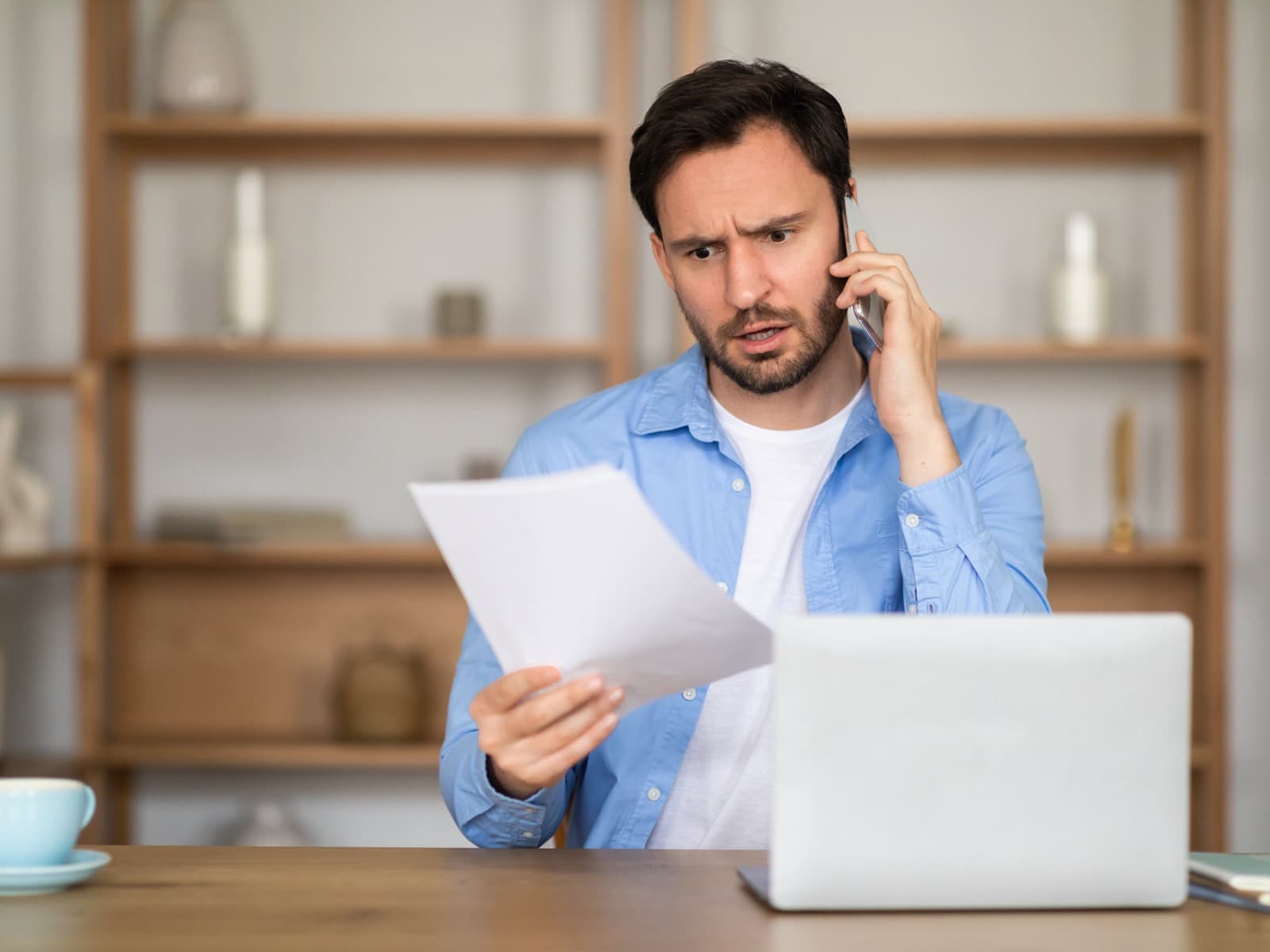 Man reviewing a document while on a phone call.
