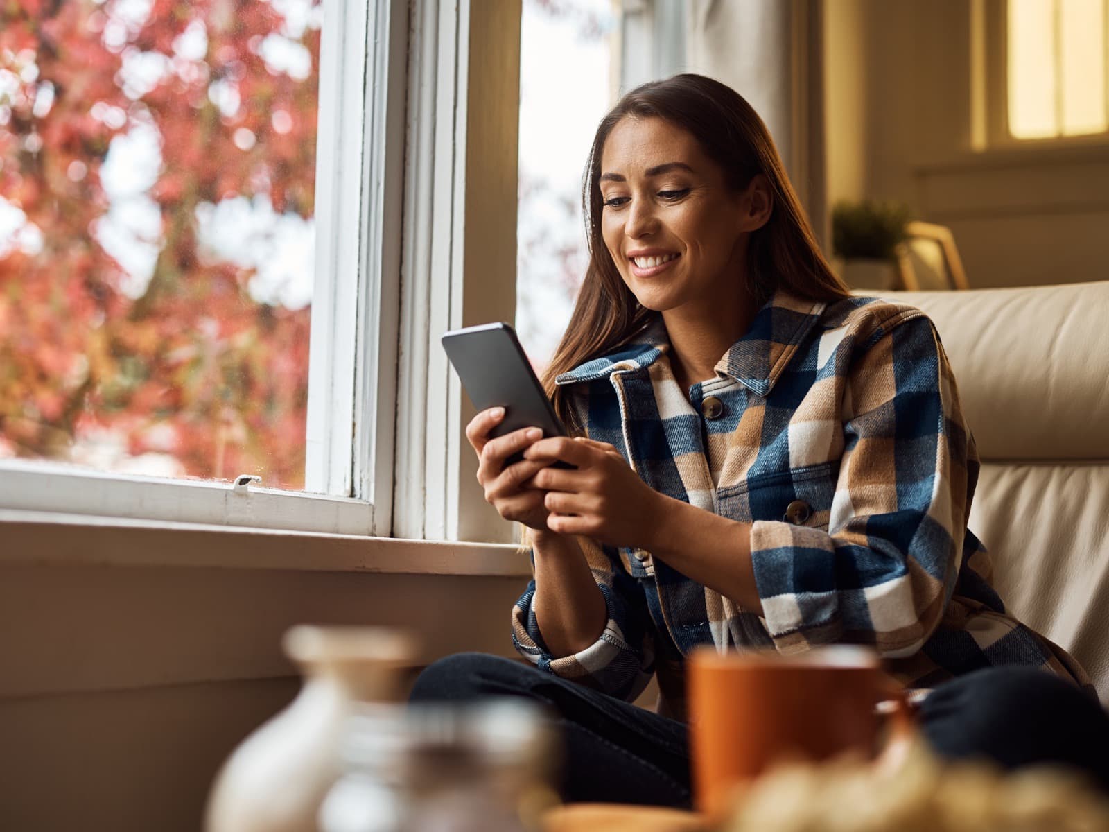 Woman smiling at her phone on the couch.