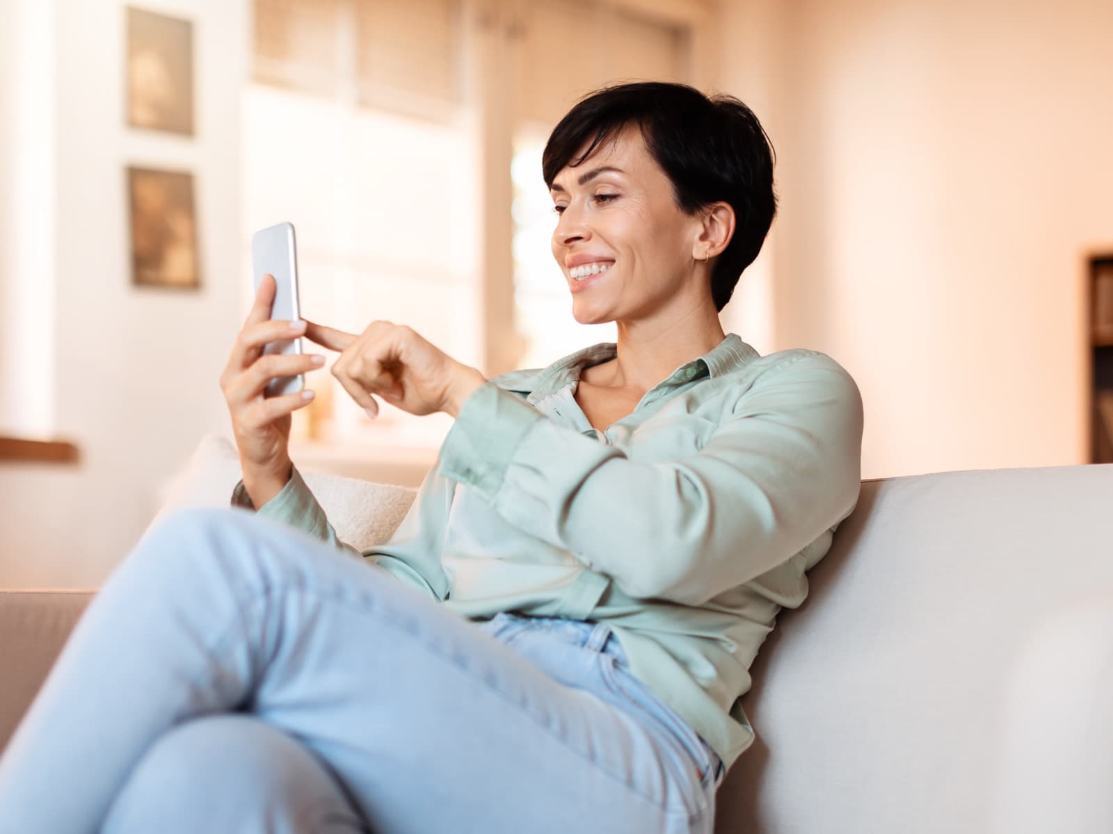 Woman using her smartphone on the sofa at home.